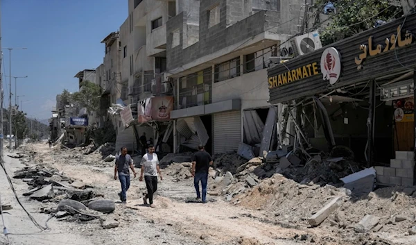 Palestinians walk along a damaged road following an Israeli attack in Nur Shams refugee camp, near the West Bank town of Tulkarem, Monday, July 1, 2024 (AP Photo/Majdi Mohammed)