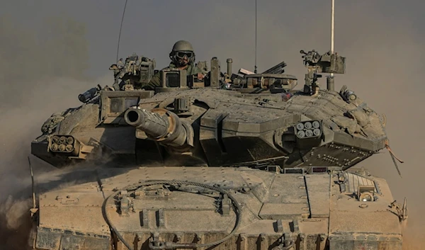 An Israeli soldier moves on the top of a tank near the separation line with Gaza, as seen from southern occupied Palestine, Sunday, July 14, 2024. (AP Photo/Tsafrir Abayov)