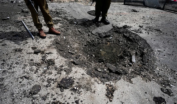 Israeli security forces examine the site hit by a rocket fired from Lebanon, in Kiryat Shmona, northern occupied Palestine, Wednesday, March 27, 2024. (AP)