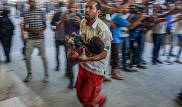 A paramedic carries a child wounded during Israeli bombardment to the emergency ward at Nassr hospital in Khan Younis, southern Gaza Strip, July 9, 2024. (AFP)