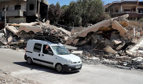 A car drives by a destroyed house that was hit by an Israeli airstrike, in Aita al-Shaab village, south Lebanon, June 29, 2024 (AP)