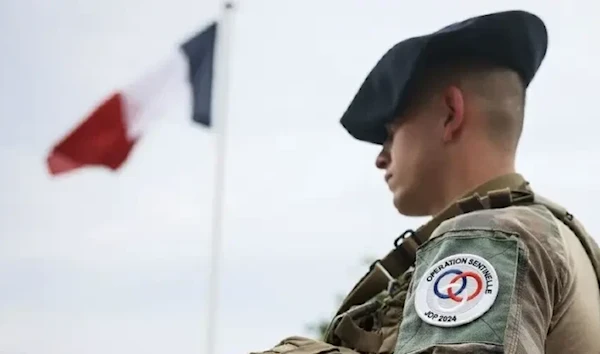 A soldier stands by the French flag at the military camp set up in the Vincennes woods, Monday, July 15, 2024 just outside Paris. (AP)