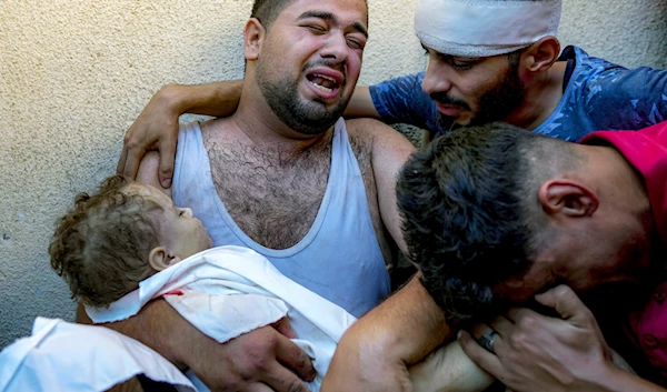 Palestinian Mahmoud Mikdad morns as holding the body of his 21-month-old child Yaman, killed in the Israeli bombardment of the Gaza Strip, at a hospital morgue in Deir al-Balah, on July 16, 2024. (AP)