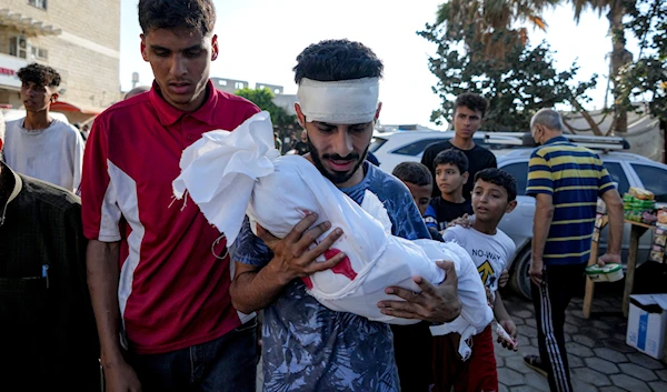 A relative holds the body of a child killed in the Israeli bombardment of the Gaza Strip, at a hospital morgue in Deir al-Balah, Tuesday, July 16, 2024. (AP)