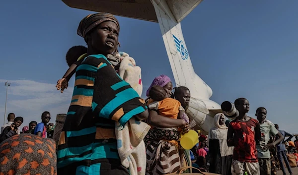 A woman and her baby daughter wait with hundreds of South Sudanese refugee returnees at Palouch airport in Upper Nile State, South Sudan, to board one of the cargo planes transporting people to different parts of the country. (UNHCR/Andrew McConnell)