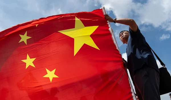 A pro-Beijing supporter holds Chinese flag to mark the 27th anniversary of Hong Kong's return to Chinese rule in Hong Kong, Monday, July 1, 2024. (AP Photo/Chan Long Hei)