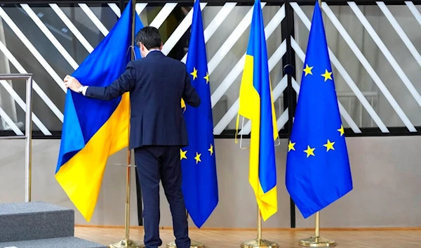 A member of protocol arranges the Ukrainian and EU flags during an EU summit at the European Council building in Brussels on Thursday, Feb. 9, 2023. (AP)