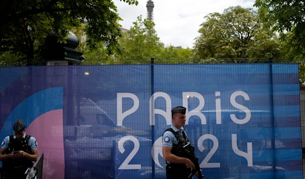 Police officers patrol near the Eiffel Tower, partially seen in background, at the 2024 Summer Olympics, Monday, July 22, 2024, in Paris, France. (AP Photo/Natacha Pisarenko)