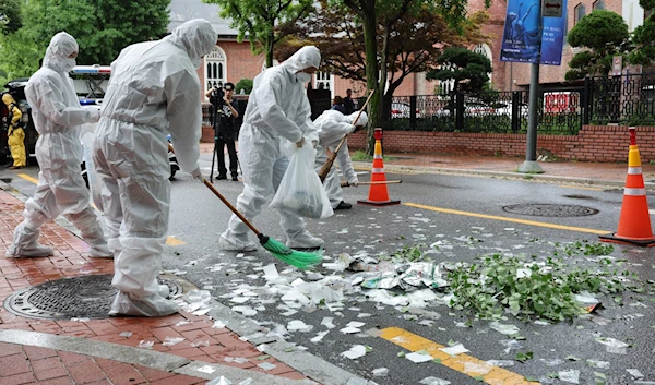 South Korean officials clean up the contents of a trash-carrying balloon sent by the DPRK after it landed on a street in Seoul on July 24, 2024. (AFP)