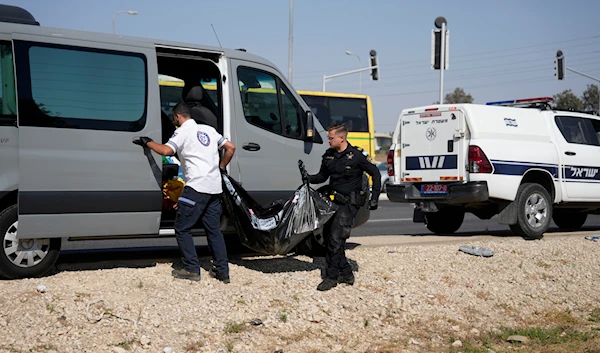 An Israeli occupation Police officer and paramedic remove a body found on June 13, 2024, in southern occupied Palestine (AP)