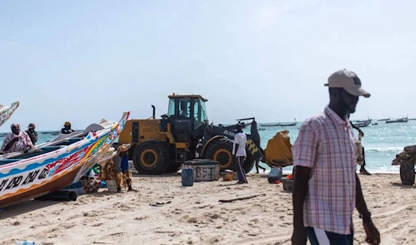 An earth-moving machine transporting bodies of migrants who perished in a shipwreck off the coast of Mauritania drives away on a beach outside Nouakchott on July 24, 2024. (AFP)