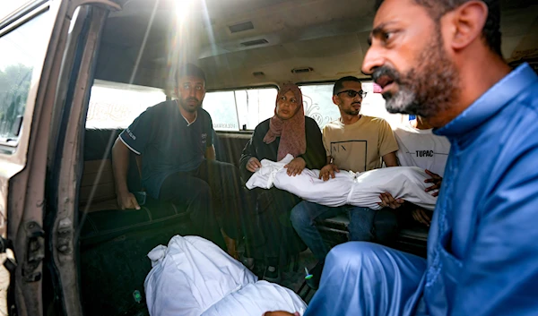 Palestinians hold the bodies of their relatives killed in the Israeli bombardment of the Gaza Strip, at a hospital morgue in Deir al-Balah, July 16, 2024 (AP)