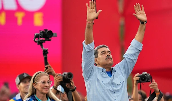 President Nicolas Maduro, accompanied by first lady Cilia Flores, raises his arms during his closing election campaign rally in Caracas, Venezuela, Thursday, July 25, 2024. Maduro is seeking a third term in the July 28 vote. (AP)