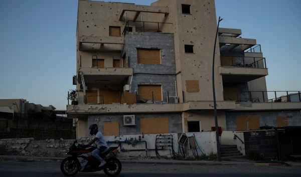 A man drives his motorcycle past a damaged building, from previous shelling attacks from Lebanon, in Kiryat Shmona, northern Israel, Wednesday, June 19, 2024. (AP)