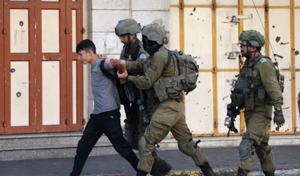 Israeli occupation forces detain a Palestinian youth in the Bab al-Zawiya area in the Palestinian city of al-Khalil in the occupied West Bank on September 29, 2022. (AFP)