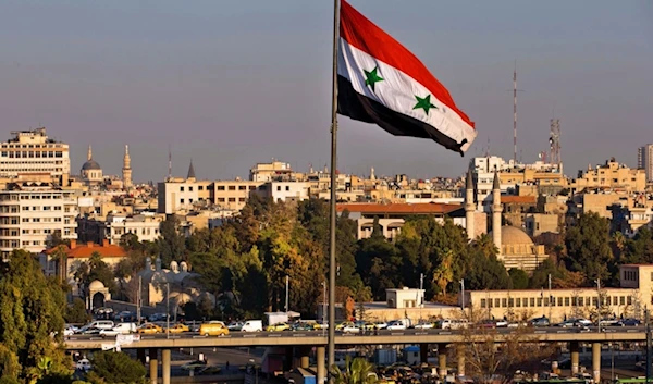 A Syrian national flag waves as vehicles move slowly on a bridge during rush hour, in Damascus, Syria, on Feb. 28, 2016. (AP)