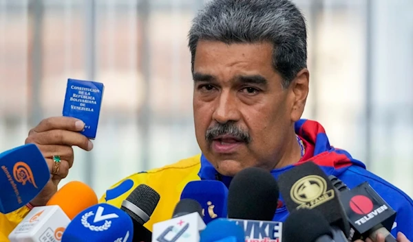 President Nicolas Maduro displays a mini edition of Venezuela's constitution after voting in the presidential elections in Caracas, Venezuela, Sunday, July 28, 2024. (AP)