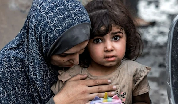 A Palestinian mother with her daughter sits near destroyed houses following airstrike in Rafah on the southern Gaza strip on November 6,2023. (AFP via Getty Images)