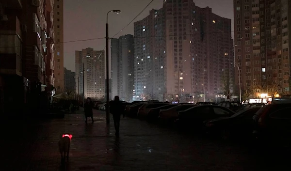 A dog with a lit up collar walks in a street during a blackout in Kiev, Ukraine, Wednesday, Nov. 16, 2022.