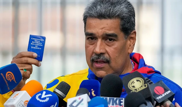 President Nicolas Maduro displays a mini edition of Venezuela's constitution after voting in the presidential elections in Caracas, Venezuela, on July 28, 2024. (AP)