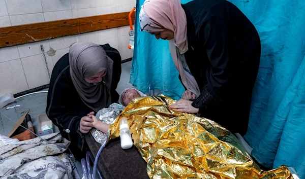 Amal Abdel-Hadi, left, and Nour Abdel-Hadi, right, react over their 2-year-old wounded niece, Siwar, as she receives treatment at a hospital in Deir al-Balah, Wednesday, July 24, 2024. (AP)