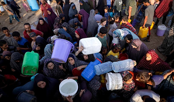 Palestinians displaced by the Israeli bombardment of the Gaza Strip queue for water at a makeshift tent camp in the southern town of Khan Younis, Monday, July 1, 2024. (AP)