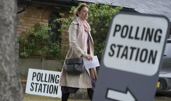 Woman holds voting card as she arrives to a vote in London in local elections, May 2, 2024. (AP)