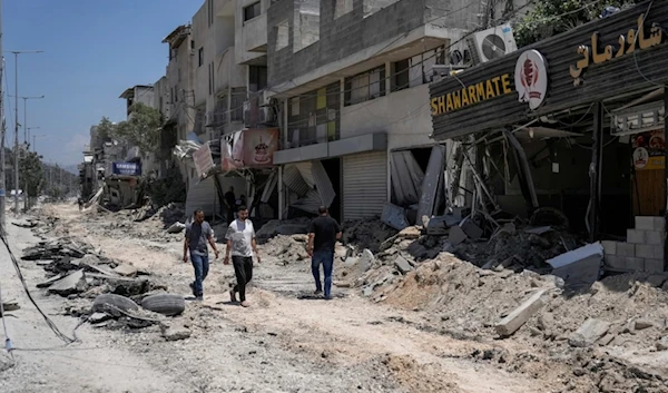 Palestinians walk along a damaged road following an Israeli occupation forces operation in Nur Shams refugee camp, near the West Bank town of Tulkarm, Palestine, July 1, 2024. (AP)