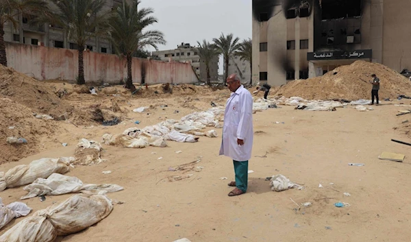 A doctor stands near bodies lined up for identification after they were unearthed from a mass grave found in the Nasser Medical Complex, southern Gaza Strip, Palestine, April 25, 2024. (AFP)