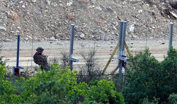 An Israeli soldier adds a new fence alongside the border wall with Lebanon as seen from the Lebanese side of the Lebanese-occupied Palestinian border in the southern village of Marwaheen, Lebanon, Friday, October 13, 2023 (AP)