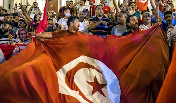 Tunisians celebrate the exit polls indicating a vote in favor of the new Constitution, in Tunis, late Monday, July 25, 2022. (AP)