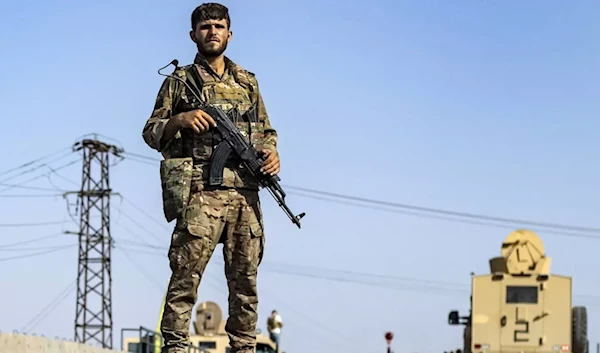 A Syrian Democratic Forces member stands guard along a road in town of al-Busayrah in Syria's Deir Ezzor province, on 4 September 2023 (AFP)