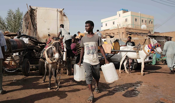 People gather to collect water in Khartoum, Sudan, on May 28, 2023, during a weeklong truce, brokered by the US and the Saudis (AP)