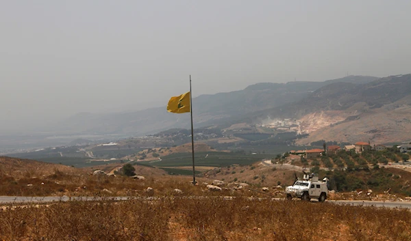 A UN vehicle patrols near a Hezbollah flag at the border in the southern village of Kfar Kila, in southeast Lebanon, July 28, 2020 (AP)