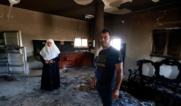 A Palestinian family stands inside their damaged home, a day after an attack by Israeli settlers on the village of Jit near Nablus in the West Bank killing a 23-year-old man dead and others with critical gunshot wounds, on August 16, 2024. (AFP)