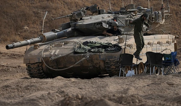 An Israeli occupation soldier jumps from the top of a tank in an area near the Israeli-Gaza border, Wednesday, July 24, 2024. (AP)