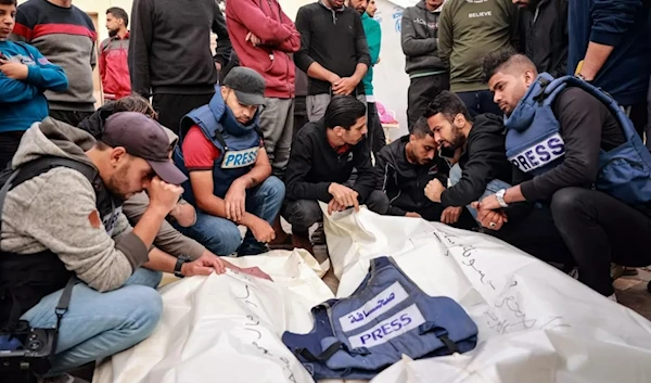 Friends and colleagues of two Palestinian journalists, Hasouna Slim and Sari Mansoor, killed in an Israeli strike, mourn over their bodies during their funeral in Deir al-Balah in southern Gaza, on November 19, 2023. (AFP)