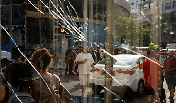 People are seen through a broken window next to the scene of an explosive drone attack in Tel Aviv, Israel, Friday, July 19, 2024. (AP)