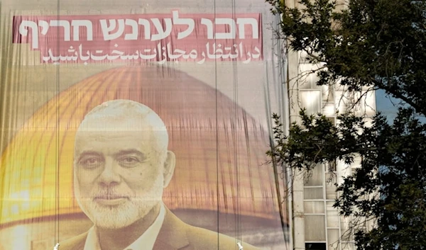 Iranian workers install a huge banner on a wall showing a portrait of Hamas leader Ismail Haniyeh with a sign which reads in Farsi and Hebrew: "Wait for severe punishment," at Palestine Sq. in Tehran, Iran, Wednesday, July 31, 2024. (AP)