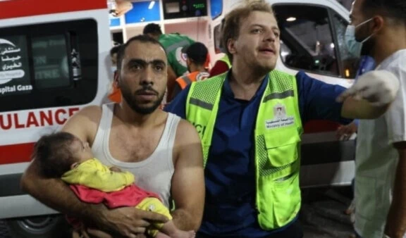 A man transports an injured Palestinian baby into al-Shifa hospital in Gaza following a brutal Israeli airstrike on October 11,2023. (AFP)