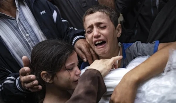 Palestinian children crying while holding the body of their mother who was killed in an Israeli airstrike on Gaza in November 2023 (AP)