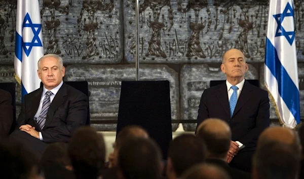 Then outgoing Israeli occupation Prime Minister Ehud Olmert, sits with now incumbent occupation PM Benjamin Netanyahu during a handover ceremony in al-Quds, occupied Palestine, April 1, 2009. (AP)