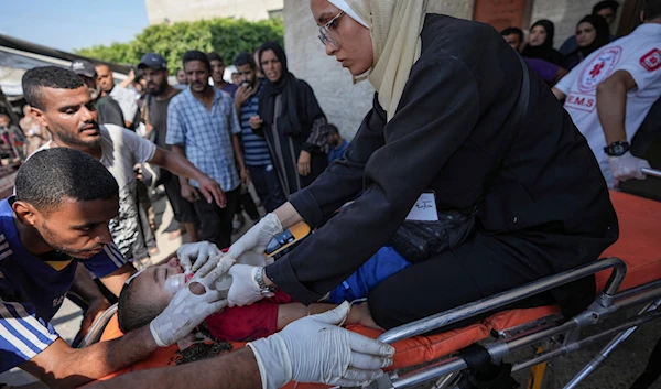 A Palestinian medic helps a child wounded in the Israeli bombardment of the Gaza Strip in a hospital in Deir Al-Balah, on July 27, 2024. (AP)