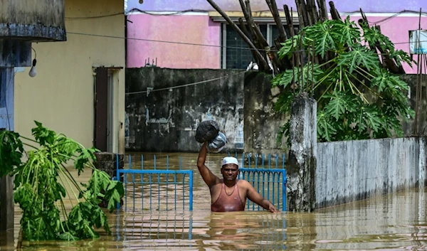 A man carrying his belongings wades through flood waters in Feni, in south-eastern Bangladesh, on August 23, 2024. (AFP)