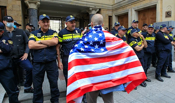 A demonstrator draped in an American flag stands in front of police during an opposition protest against the foreign influence bill at the Parliamentary building in Tbilisi, Georgia, Tuesday, May 28, 2024. (AP)