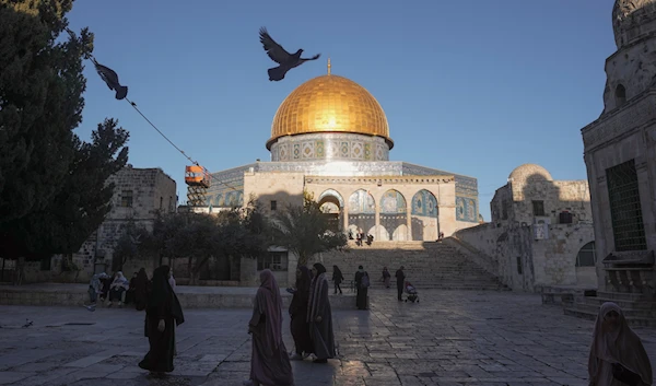 People walk next to the Dome of Rock Mosque at the al-Aqsa Mosque compound in al-Quds' Old City, occupied Palestine, March 10, 2024 (AP)