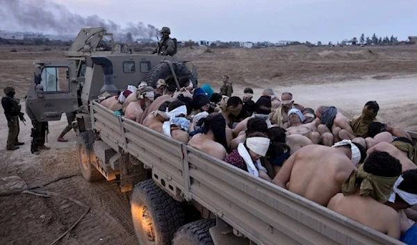 Israeli occupation forces stand next to a truck packed with bound and blindfolded Palestinian abductees in Gaza, December 2023. (AP)