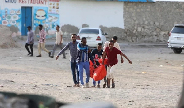 Somalians carrying a body after a terrorist attack on Lido Beach in Mogadishu, Somalia on August 3, 2024 (AFP)