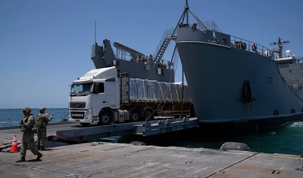 A U.S. Army soldier gestures as trucks loaded with humanitarian aid arrive at the U.S.-built floating pier Trident before reaching the beach on the coast of the Gaza Strip, Tuesday, June 25, 2024. (AP)