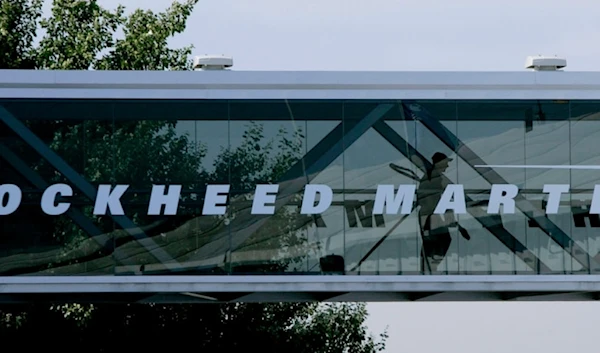 A man walks past a Lockheed Martin logo as he walks through a section of the company's chalet bridging a road at Farnborough International Airshow in Farnborough, southern England, July 19, 2006. (AP)